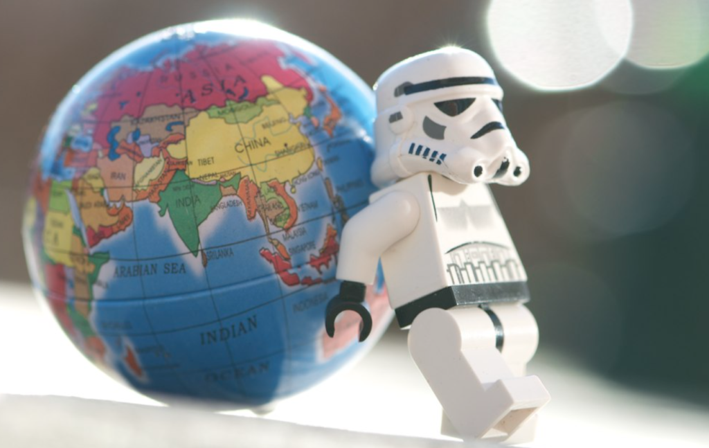 A lego stormtrooper holds up a toy globe.