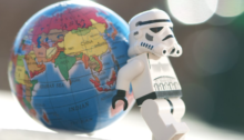 A lego stormtrooper holds up a toy globe.